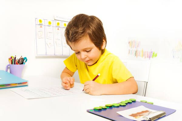 Boy concentrating while writing with pencil