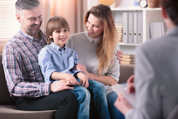 Happy kid sitting on his father's lap next to his mother during a meeting