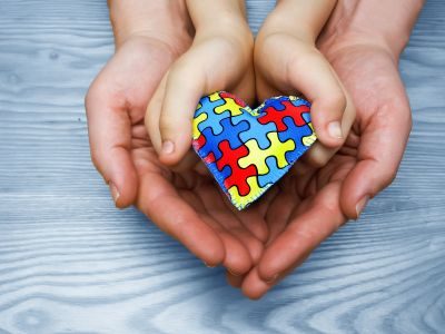 Hands holding autism awareness puzzle heart
